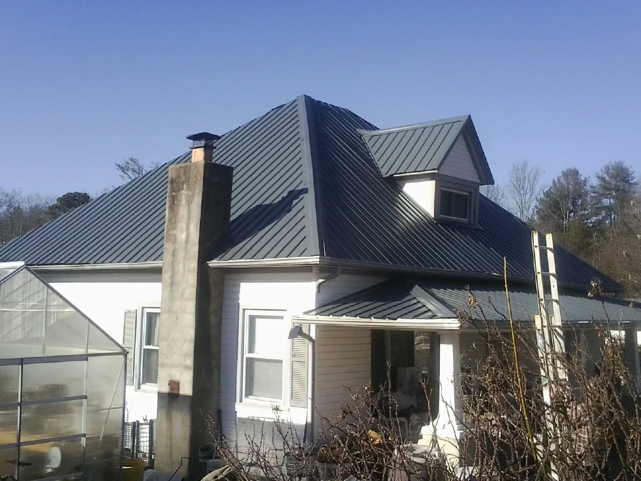 Dark blue standing seam metal roof on a white farmhouse with dormer — Slate & Tile Roof Repair by Roofing Brothers in Vista