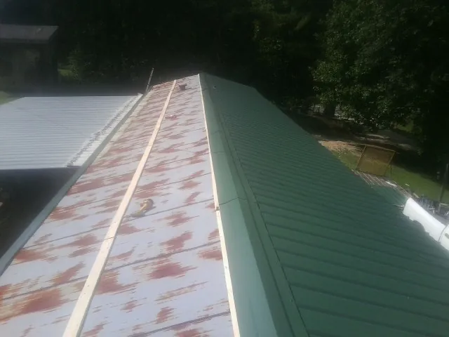 Old rusted panels beside newly installed green metal roofing — Wind Damage Roof Repair by Roofing Brothers in Vista