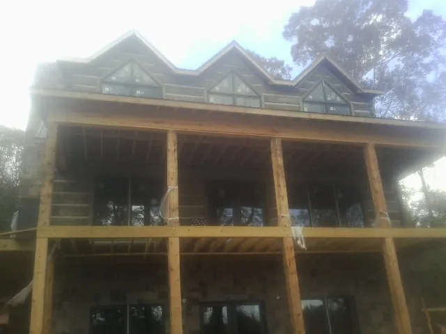 Dormers and porch framing on a large log home under construction — Roof Coating work by our crew in Vista
