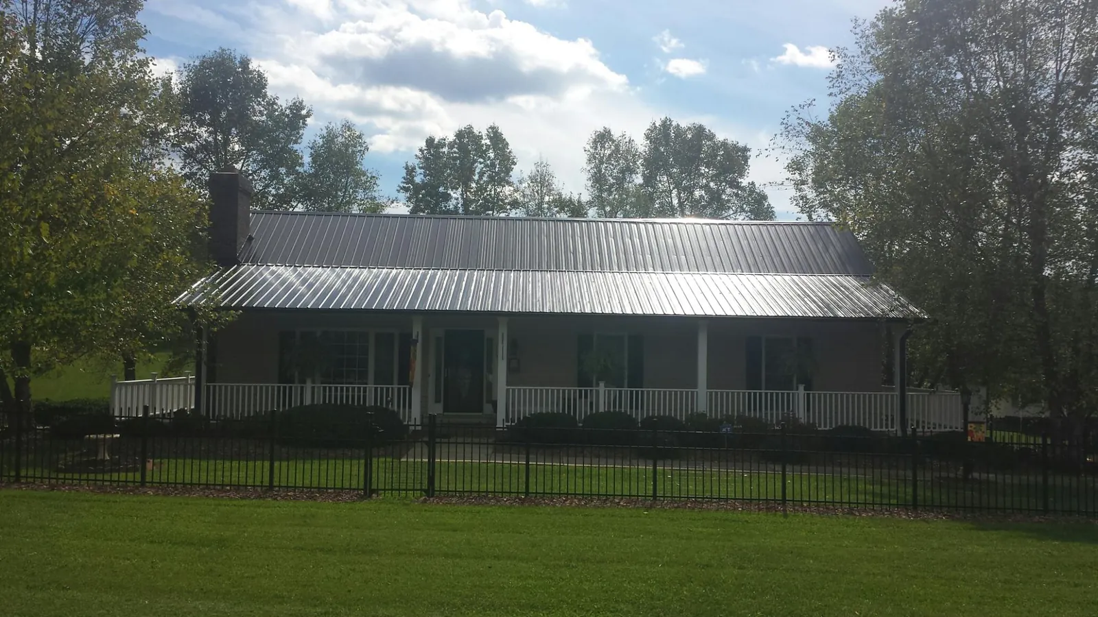 Gray metal roof on a brick ranch with a full width front porch — Gutter Guard Installation work by our crew in Vista