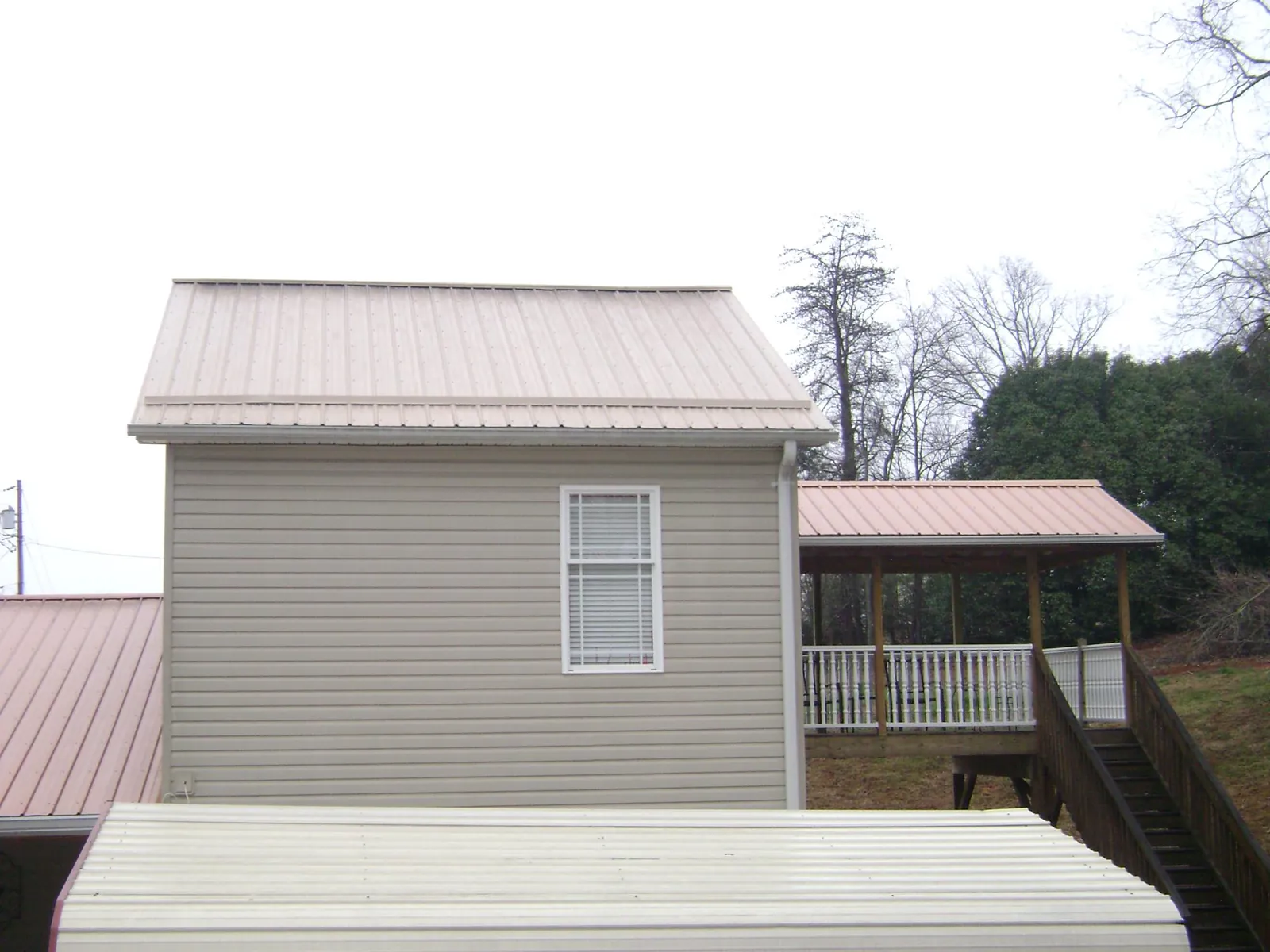 Tan metal roofs on a two story addition and attached porch, from a Roof Replacement job in Vista