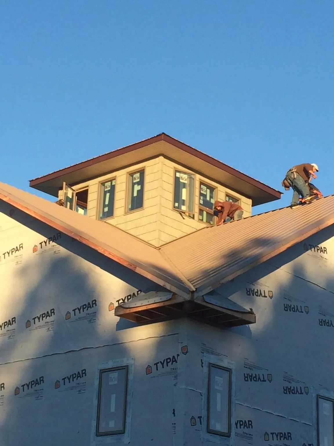Roofers working around a rooftop cupola on a new metal roof at sunset — Roof Waterproofing in Vista by Roofing Brothers